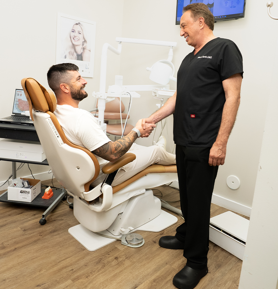 doctor Sarris shaking hand of a patient in a dental chair in the office